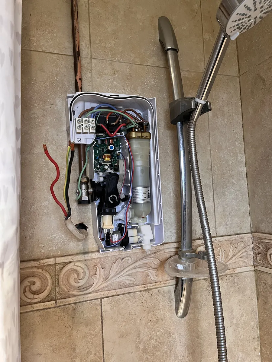 Electric shower unit open for repair showing the heater can and wiring