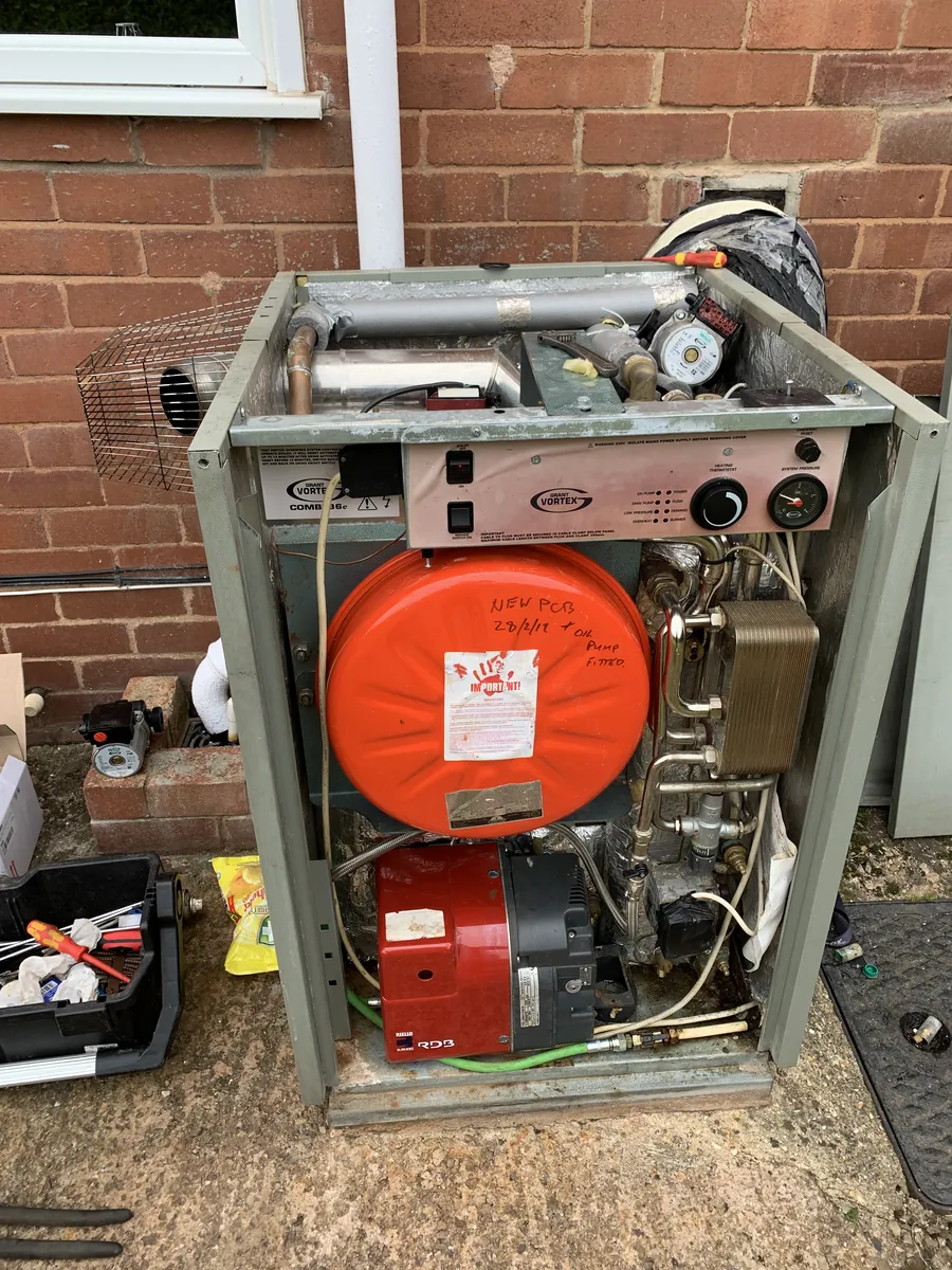 Grant Vortex external oil boiler open for repair against a brick wall in Exeter