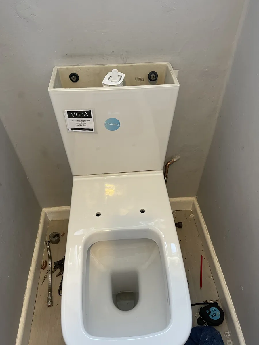 Close-coupled toilet with the cistern lid off showing a new flush valve, Exeter