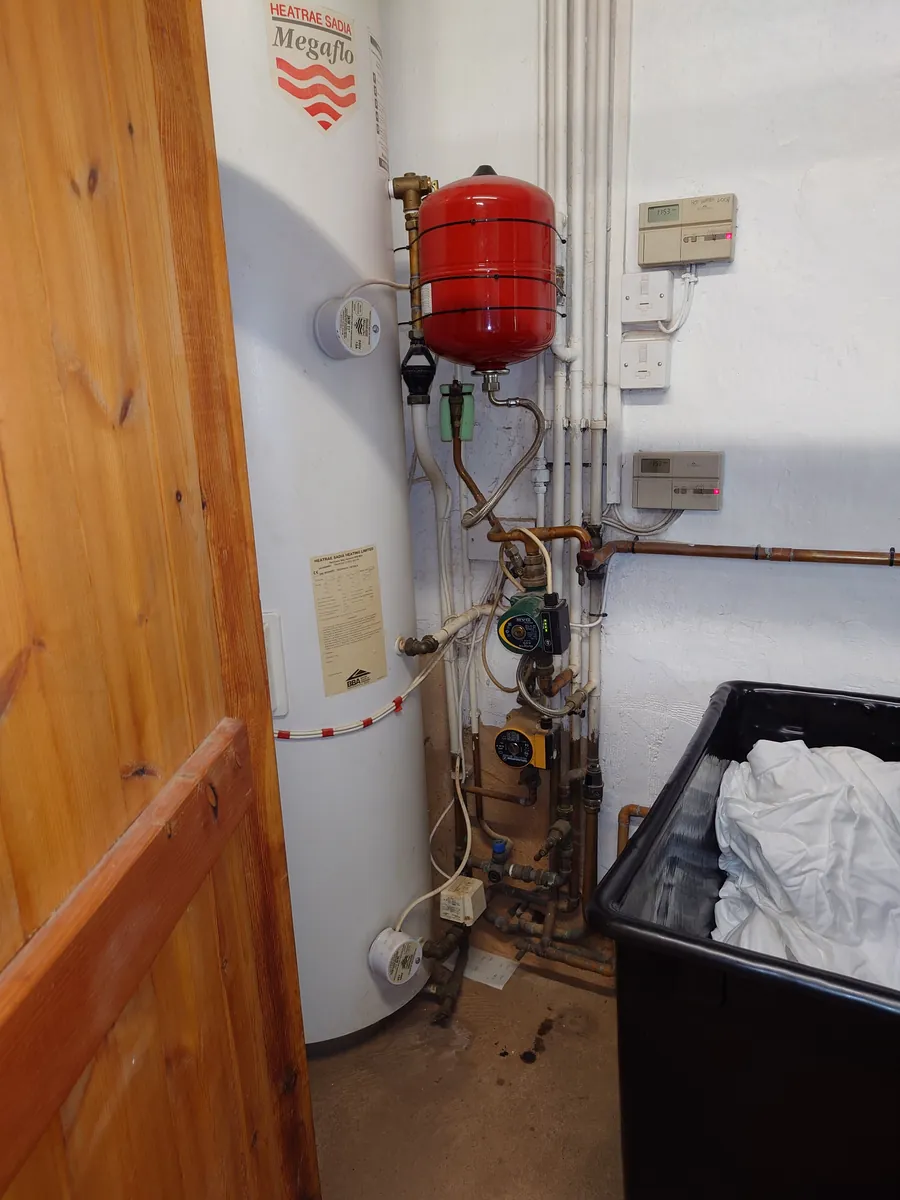 Unvented hot water cylinder in an airing cupboard with its red expansion vessel, Exeter